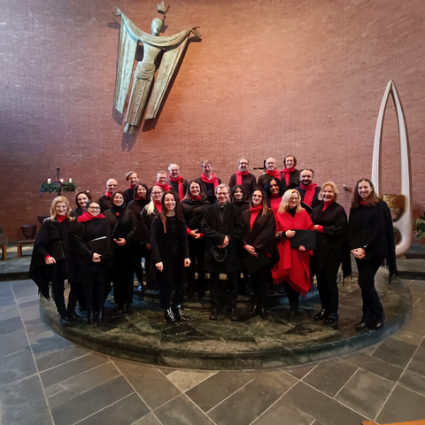 Stoimy na tle ołtarza modernistycznego, nowoczesnego kościoła o prostym, surowym wystroju. W tle, na ceglanej ścianie kamienna rzeźba zmartwychwstającego Chrystusa, który przedstawiony jest jako postać lecąca w stronę nieba.